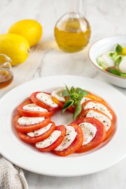 Dilimlenmiş RedTtomato, Mozzarella ve Basil ile salata Caprese, Beyaz Seramik Masa 'da servis edilir. 