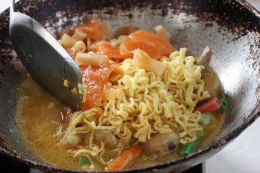 Seblak 'ı Rustik Pan' da pişiren Seblak, Bandung Popüler Sokak Gıda Karışımı Sosis, Köfte, Erişte ve Kraker gibi Varius Topping. 