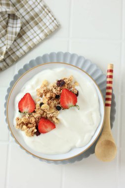 Tahta kaşıkla seramik kasede servis edilen, Granola ve Çilek Tepeli Yunan yoğurdu