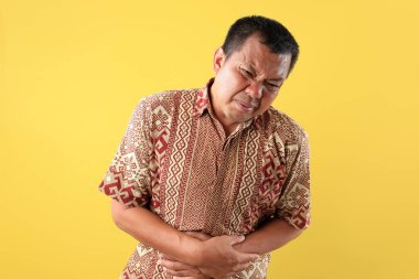 Asyalı Orta Çağ Adamı 'nın portresi, Midede El, Mide Ache, İshal, Kabızlık, Mide iltihabı, Hazımsızlık. Sarı Arkaplanda İzole Edildi 