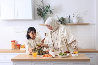 Anne ve kızı evde bayram kutlaması için Ketupat Lebaran 'ı hazırlıyorlar. Lebaran veya Idul Fitri Konsepti 