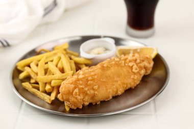 Fish and Chips, un hamurunda kızarmış balık, patates kızartması ve kola ile servis edilir. Metalik Plaka Servisi