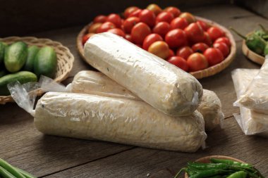 Silindir Şekli Raw Tempeh ya da Tempe ve Plastik Paketleme Çeşitli Taze Sebzelerin yanında. Mayalanmış soya fasulyesinden yapılmış Endonezya yemeği.. 