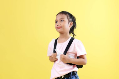 Sırt çantalı Endonezya 'lı genç çocuklar, Tepeye bakın. Okul Konseptine geri dönelim. Sarı Arkaplanda İzole Edildi.