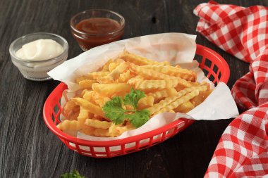 Kızarmış patates kızartması ya da Kentang Goreng, yanında da mayonez ve sos. Kara Tahta Arkaplan 'ın üstündeki Kırmızı Plastik Sepet' te servis ediliyor.. 