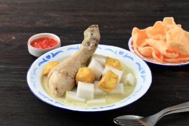 Lontong Opor Ayam Tahu, Indoensian Rice Cake ile Beyaz Köri Çorbası ve kızarmış tofu. Enamel Tabağı 'nda krakerlerle servis edildi.. 