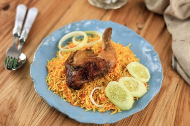 Tahta masada çay ile servis edilen Nasi Kebuli Ayam (Tavuk Pilav)