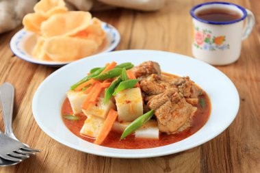 Lontong Kari Ayam merah, Endonezya Geleneksel Kahvaltı Menüsü. Sıkıştırılmış pirinç keki yanında kırmızı tavuk baharatlı baharatlı köri ve haşlanmış havuç ve uzun fasulye. Lebaran Dish için de popüler. 