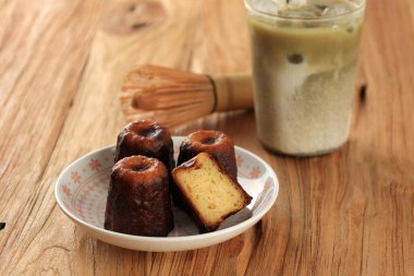 Caneles de Bordeaux, Geleneksel Fransız Tatlı Tatlısı Yeşil Çay Matcha Latte ile servis edilir, Tahta Masa üzerinde 