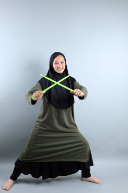 Yeşil Çubukla Poundfit Rockstar antrenmanı yapan kadın Müslüman, Gri Arkaplan 'da izole edilmiş. 