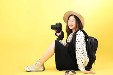 Sarı Arkaplanda, Kameralı ve Şapkalı Genç Asyalı Kız Sırt Çantası Konsepti 