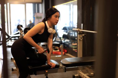 Spor salonunda müzik dinlerken dambılları kullanan genç bayan eğitimi. 