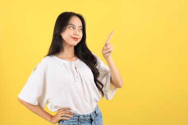 Neşeli Genç Asyalı Genç Kadın İşaret Parmağıyla Tarafını Gösterirken, Mutlu Heyecan, Öneriler, Dostça Bir Tavsiye veya Tavsiye Verirken Özgüvenle Gülümsüyor. Sarı Arkaplanda İzole Edildi 