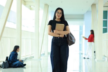 Kampüs Koridorunda duran, Gözlüklü Genç Asyalı Kız Kolej Öğrencisi Portresi