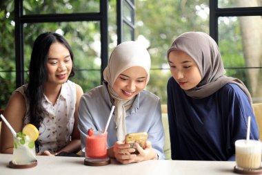 Neşeli ve Güzel Asyalı Kadın Arkadaşlardan oluşan bir grup Seyahat Ederken, Cep Telefonu Bakarken Kahve İçiyor 