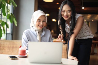 Kahve dükkanında dizüstü bilgisayarda çalışan iki Asyalı arkadaş.. 