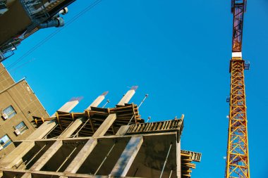 Construction crane against the blue sky. The real estate industry. A crane uses lifting equipment at a construction site.