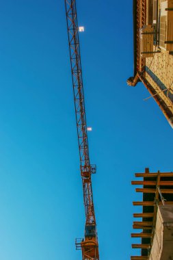 Construction crane against the blue sky. The real estate industry. A crane uses lifting equipment at a construction site.