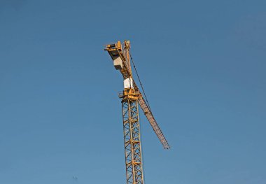 Construction crane against the blue sky. The real estate industry. A crane uses lifting equipment at a construction site.