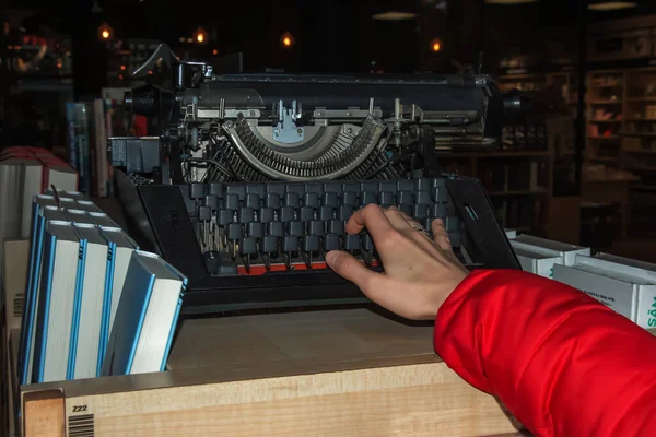 A woman\'s hand writes on an old typewriter.