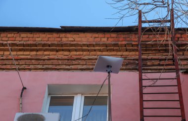 Starlink satellite dish, an internet constellation operated by SpaceX, is installed on the wall of an apartment building.