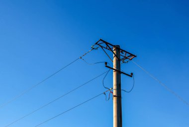Electric pole with a linear wire against the blue sky close-up. Power electric pole.