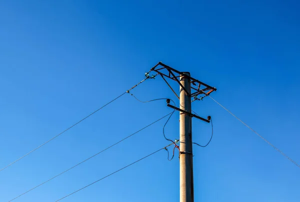 Electric pole with a linear wire against the blue sky close-up. Power electric pole.