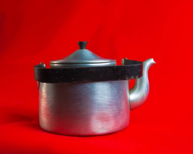 Old soldier's aluminum teapot from the Second World War on a red background.