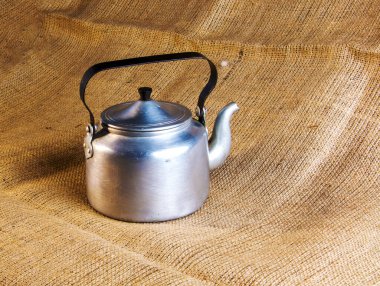 An old soldier's aluminum teapot from the Second World War against the background of burlap.
