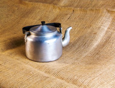 An old soldier's aluminum teapot from the Second World War against the background of burlap.