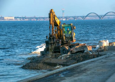 Dnepropetrovsk, Ukrayna - 11.26.2021: Kazıcı seti güçlendirmek için çalışıyor. Nehir kıyısında çalışan hidrolik kazıcı.