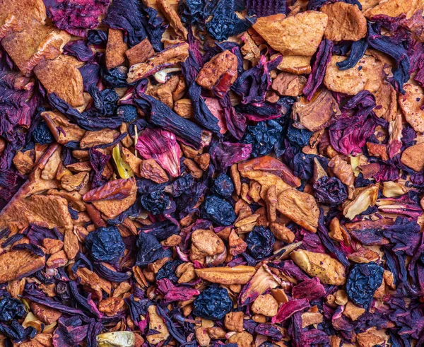 Background of natural fruit tea with hibiscus petals, fruit slices and berries. Fruit tea texture. Top view, flat lay.