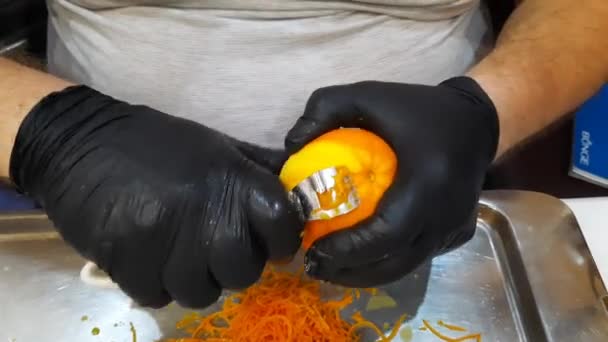 黒手袋の男性の手は特別なナイフでオレンジからゼストを削除します — ストック動画