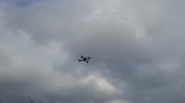Dron kuadkopteri bulutlu bir gökyüzüne doğru uçuyor ve yeşil çimlere iniyor..