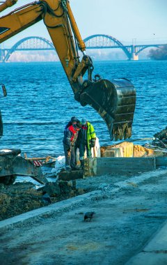 Dnepropetrovsk, Ukrayna - 11.26.2021: Kazıcı seti güçlendirmek için çalışıyor. Nehir kıyısında çalışan hidrolik kazıcı.