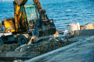 Dnepropetrovsk, Ukrayna - 11.26.2021: Kazıcı seti güçlendirmek için çalışıyor. Nehir kıyısında çalışan hidrolik kazıcı.