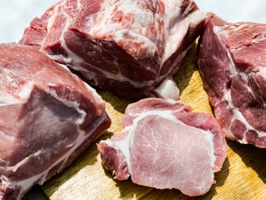 Ahşap bir mutfak tahtasının üzerinde domuz leşinin çeşitli parçalarından taze kesikler. Domuz eti parçaları. Yakın plan.