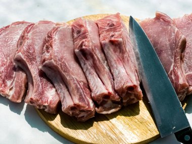 Ahşap mutfak tahtasında taze porsiyon domuz pirzolası. Domuz eti parçaları. Yakın plan.