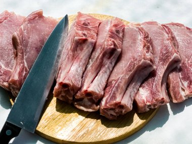 Ahşap mutfak tahtasında taze porsiyon domuz pirzolası. Domuz eti parçaları. Yakın plan.