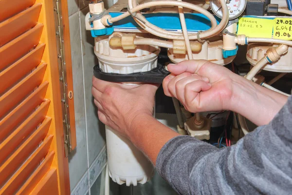 Kadınların elleri kirlenmiş su arıtma filtreleriyle dolu mataraları temizleriyle değiştirmek için kaldırıyor. Çok aşamalı su filtresinin kartuşlarını değiştirme işlemi.