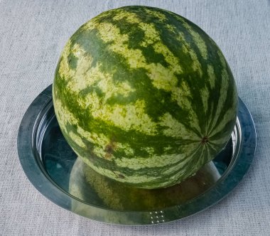 Çuval beziyle kaplı bir masanın tepsisindeki yeşil çizgili karpuz..