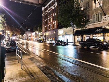 Portland, Oregon, ABD - 09.28.2023 Portland sokaklarında akşam. Kaldırımdaki trafik ışıklarının yağmur ve yansımaları.