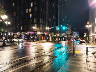 Portland, Oregon, ABD - 09.28.2023 Portland sokaklarında akşam. Kaldırımdaki trafik ışıklarının yağmur ve yansımaları.