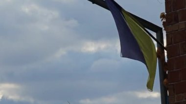 Ukrayna bayrağı rüzgarda dalgalanıyor kasvetli bir gökyüzüne karşı.