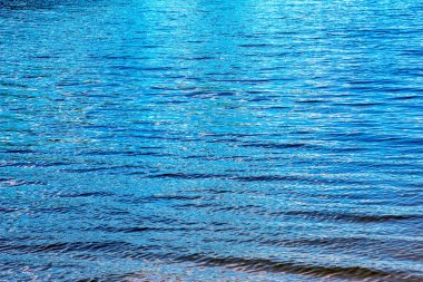 Water ripple texture background. Wavy water surface during sunset, golden light reflecting in the water.