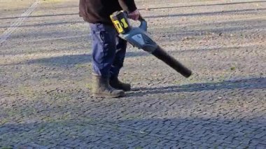 Bir işçi parktaki sonbahar yapraklarını çıkarır. Yakın plan. Şehri kışa hazırlıyorum..