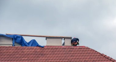 Nitra, Slovakya - 05.15.2023: Tamirciler bir evin çatısındaki bacaları onarıyor.