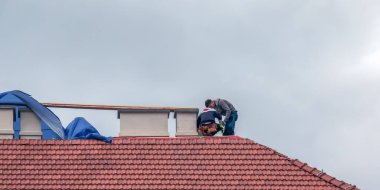 Nitra, Slovakya - 05.15.2023: Tamirciler bir evin çatısındaki bacaları onarıyor.