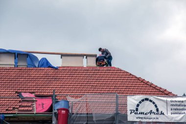 Nitra, Slovakya - 05.15.2023: Tamirciler bir evin çatısındaki bacaları onarıyor.