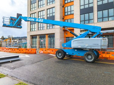 Portland, ABD - 01.27.2024: Bir binanın arka planına karşı mavi çalışma platformu. İnşaat alanında seyyar vinç.